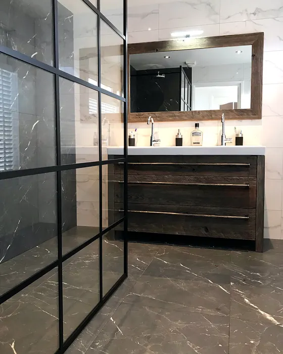 Badkamer met zwarte glazen douchewand en houten wastafelmeubel