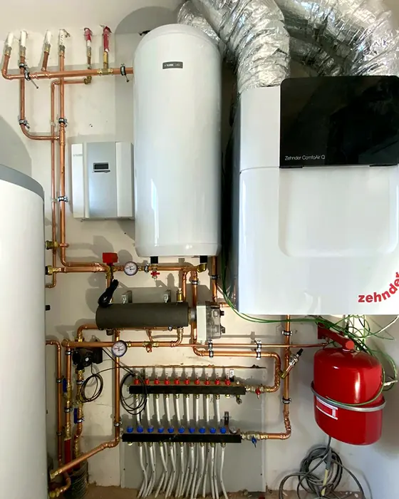 Technische ruimte met warmtepomp, boiler en verdeler met koperen leidingen